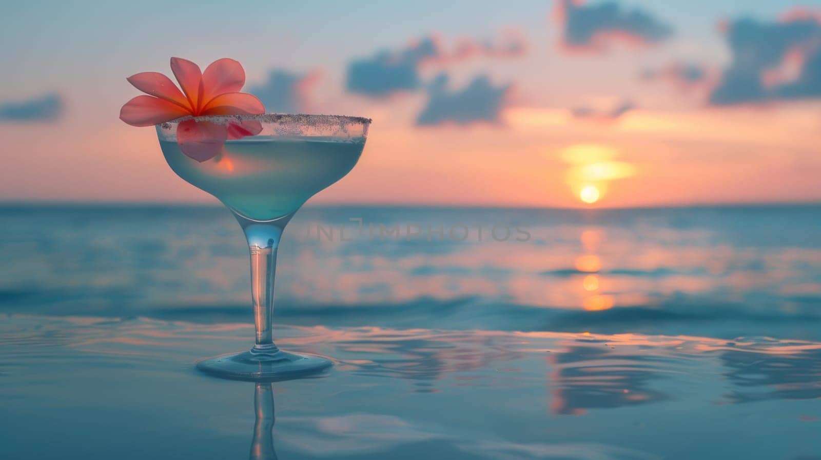 Cocktail glass with flower on sandy beach.