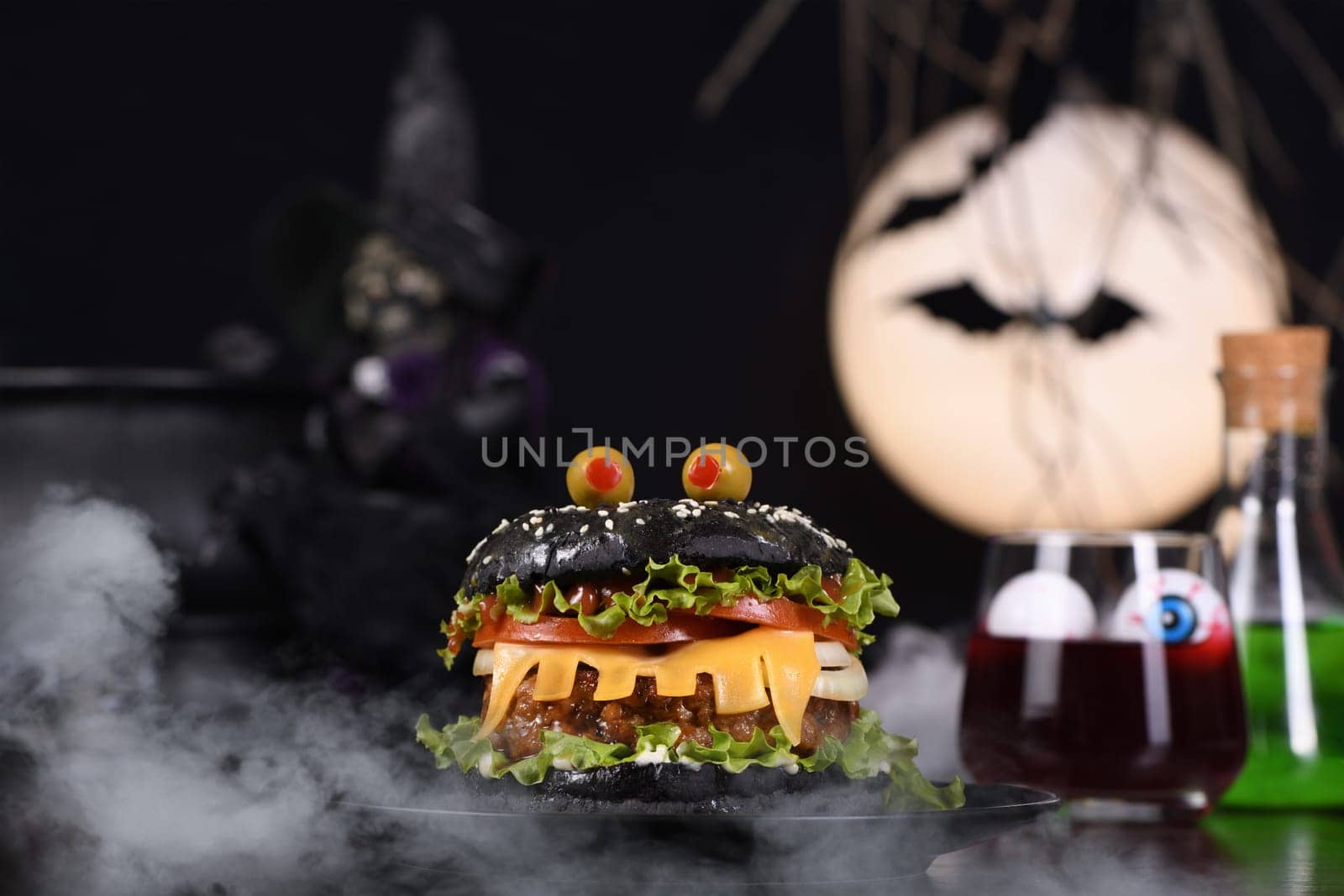 Monster Burger. Black bun, juicy beef cutlet, lettuce, onion, tomato and cheese in the shape of teeth, eyes with olives. Definitely a pick-me-up and a perfect Halloween party appetizer.