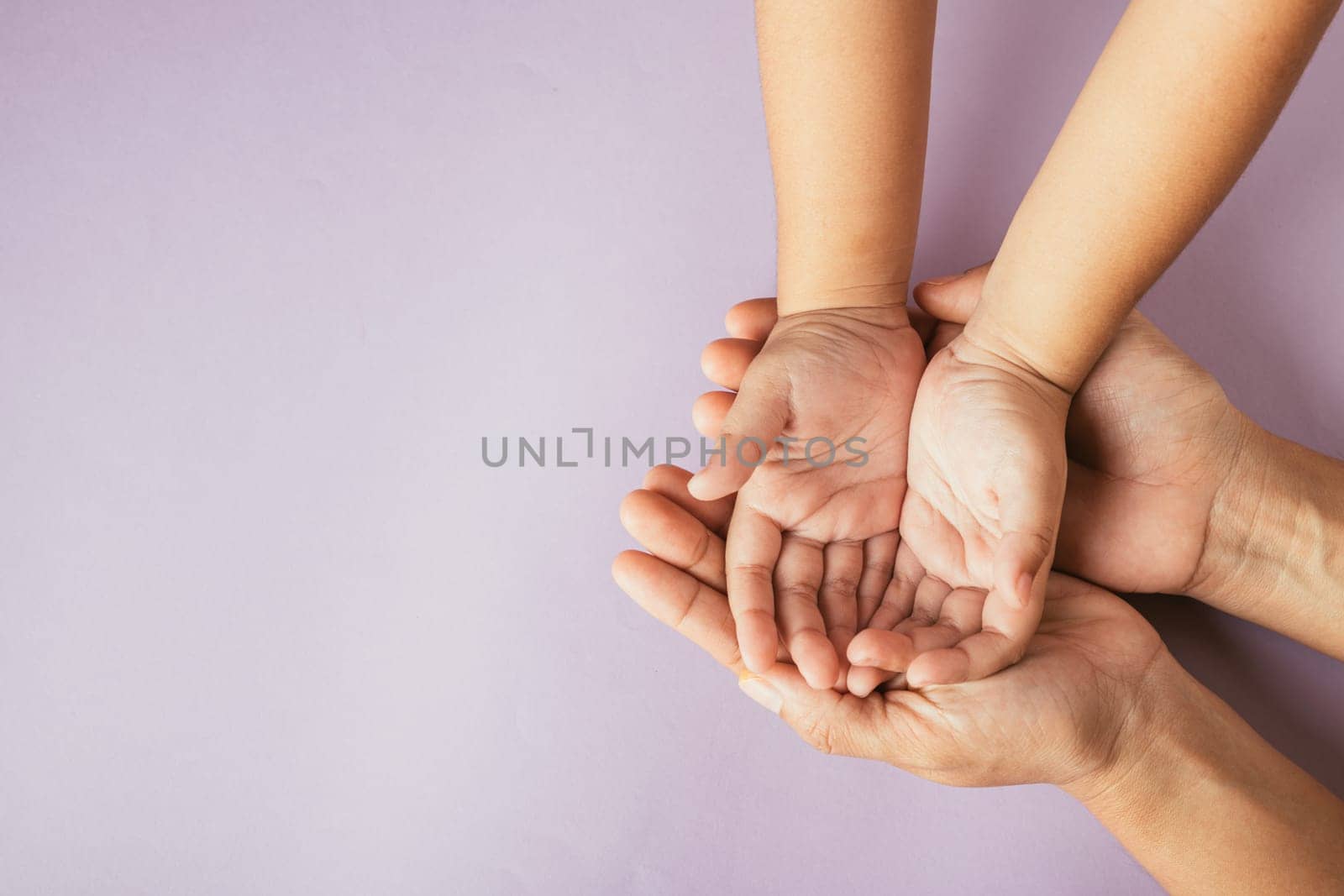Top view of parents and kid holding empty hands together on a color background. Family day celebrating togetherness and support.