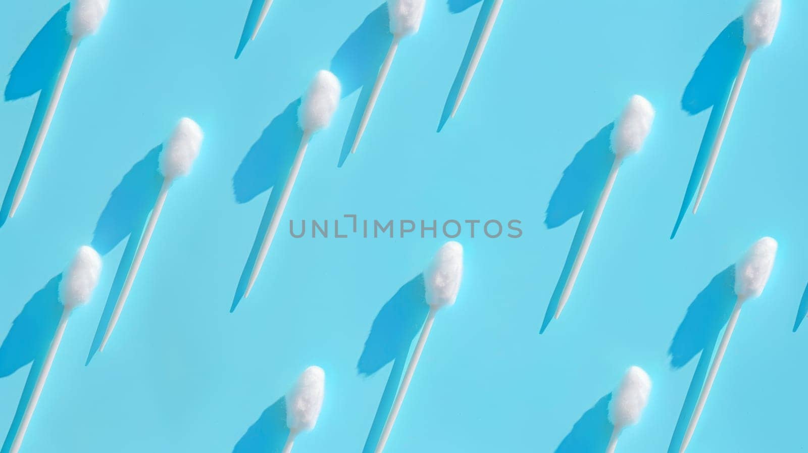 Pattern of a cotton swabs on a blue background.
