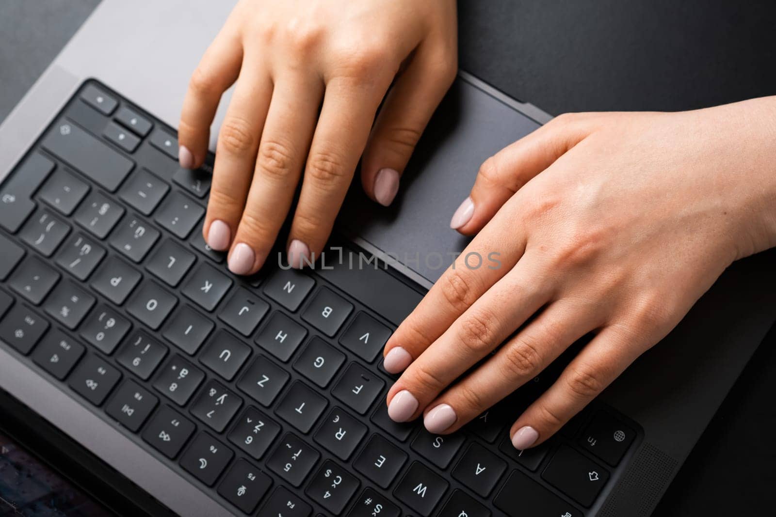BERLIN, GERMANY - APRIL 14 2024: Womans hands typing on laptop keyboard, top view.