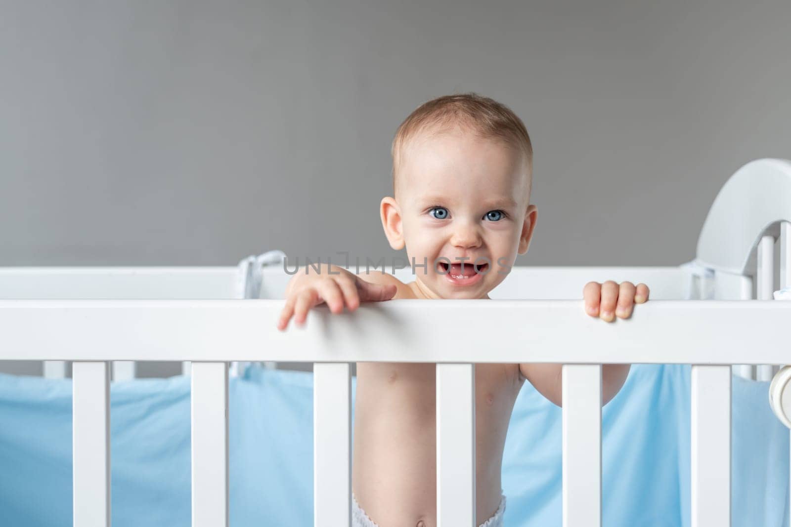 Laughing baby reaching out from his crib.