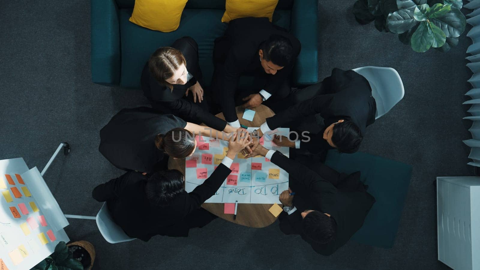 Top view of business people putting hands together and clapping hands to celebrate successful project while using kanban task board to manage time. Startup team stacking hands together. Directorate.
