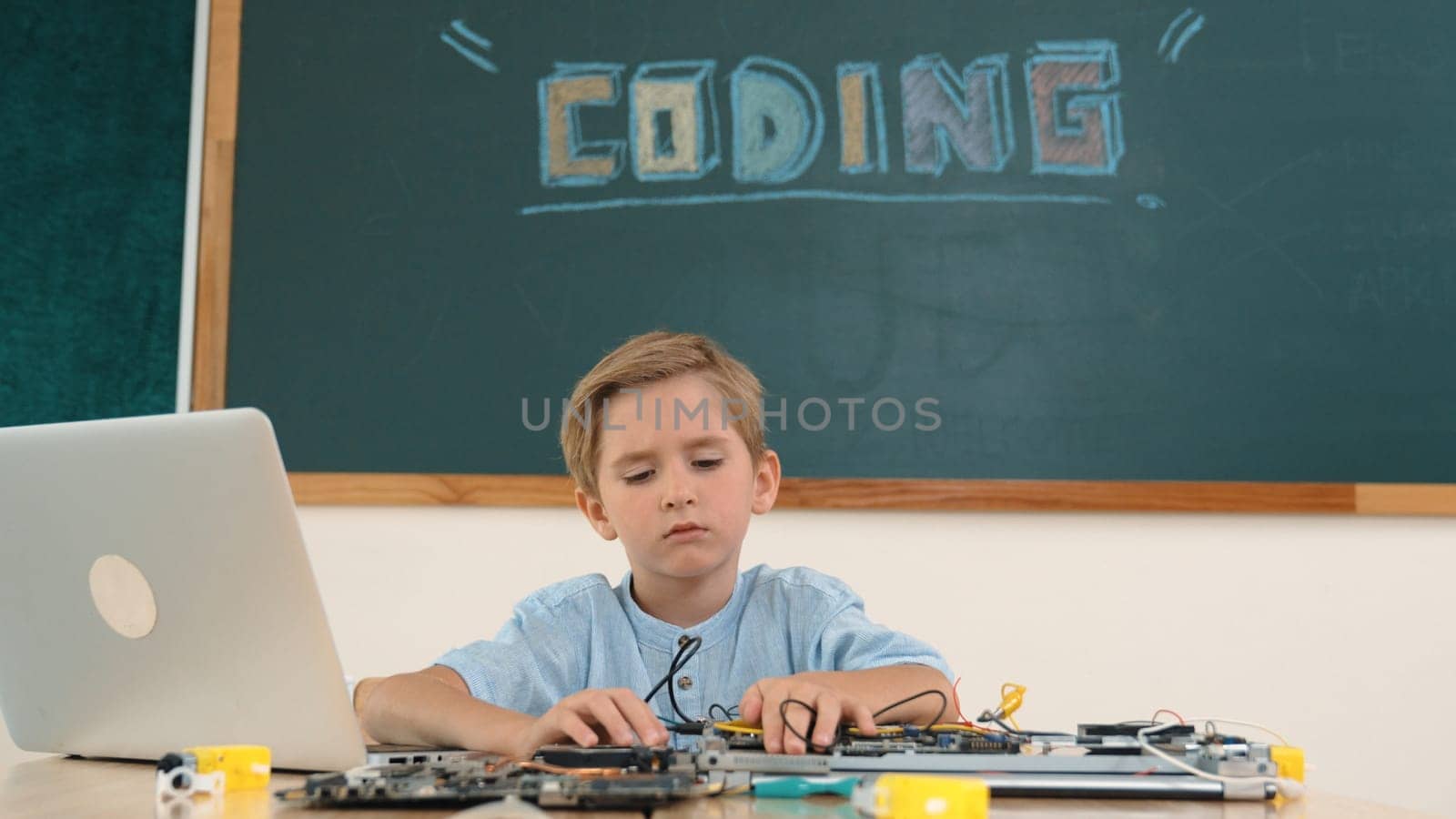 Smart student working on electronic board while looking at camera with blackboard. Child fixing main board while prepare for programing system by using coding engineering and generating AI. Pedagogy.