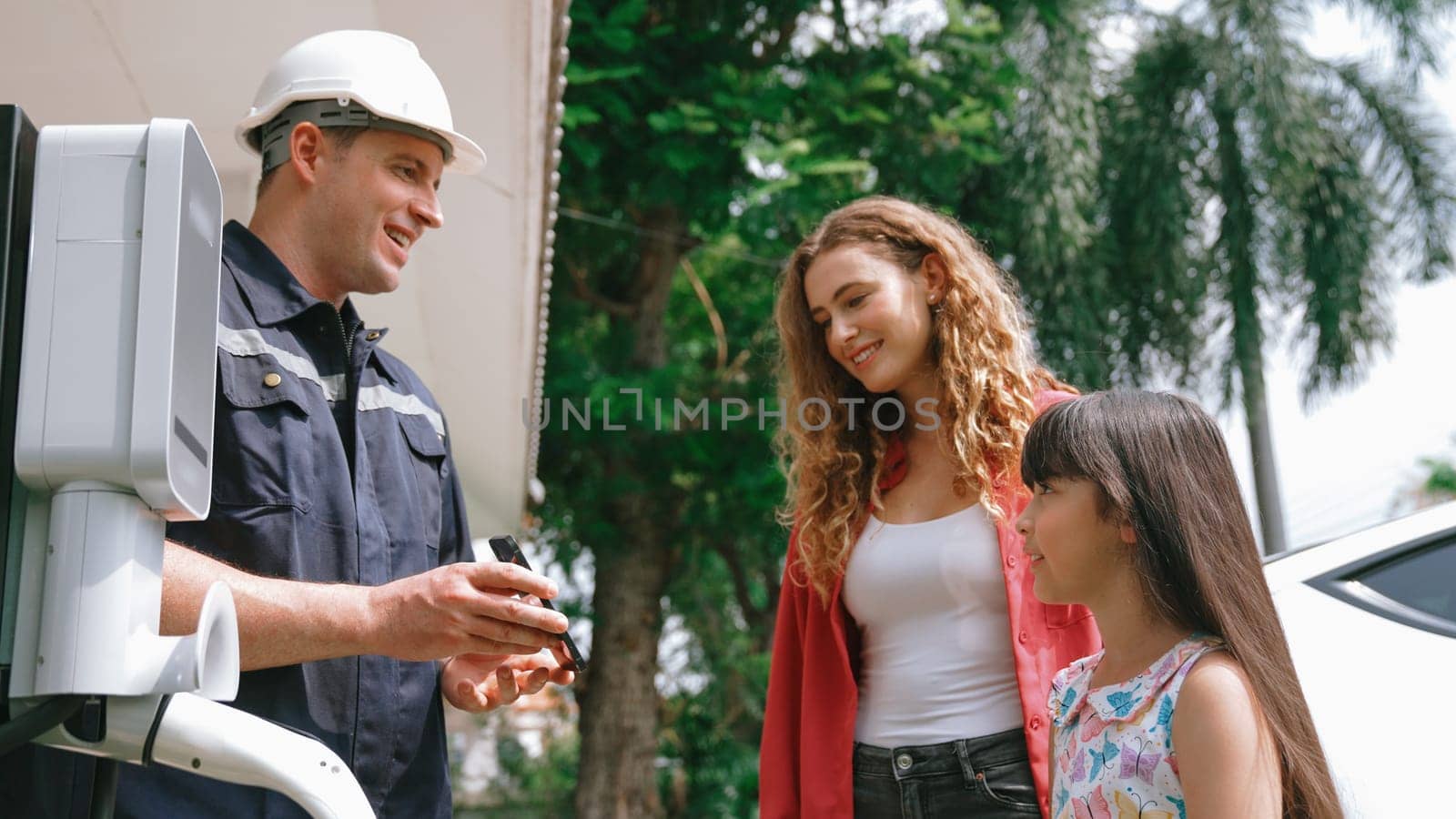 Technician install home EV charging station, providing service support for EV app on customer smartphone for monitoring charging status and set charging schedules at home. Synchronos