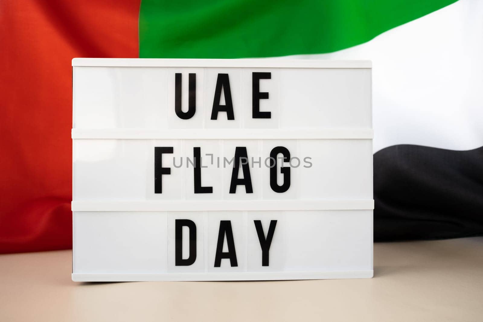 Lightbox with text UAE FLAG DAY on United Arab Emirates waving flag made from silk material. Independence Commemoration Day Muslim Public holiday celebration background. The National Flag of UAE by anna_stasiia