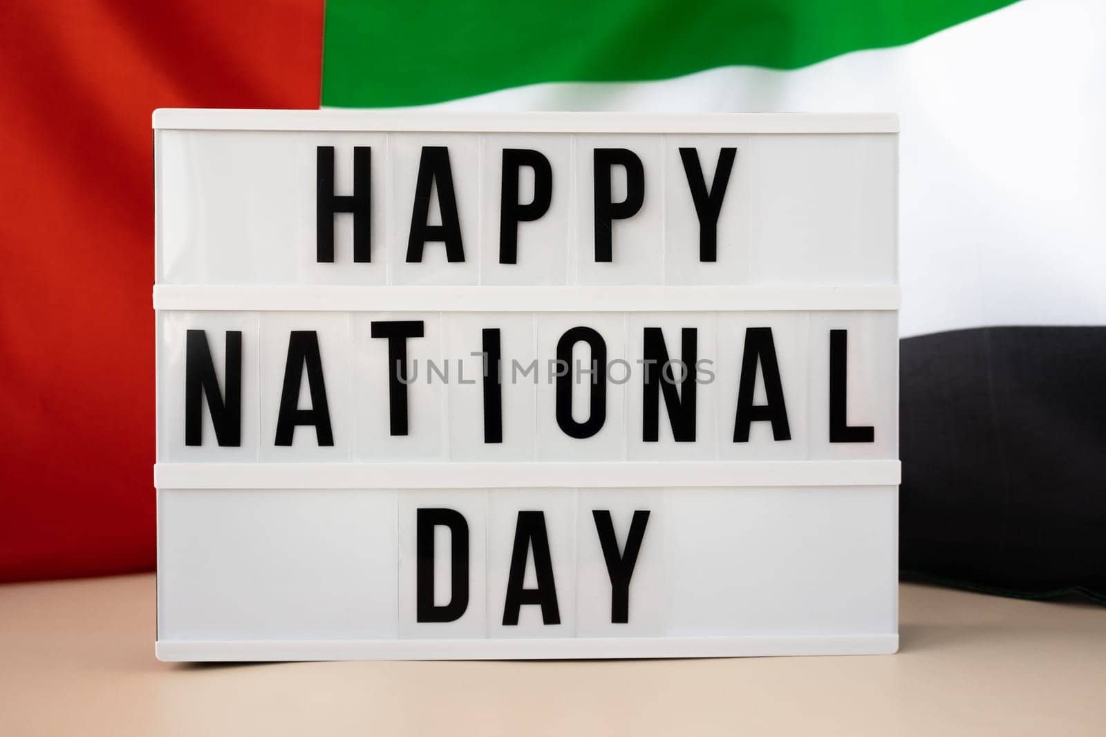 Lightbox HAPPY NATIONAL DAY text frame on United Arab Emirates waving flag made from silk material. Independence Commemoration Day Muslim Public holiday celebration background. The National Flag of UAE. Patriotism