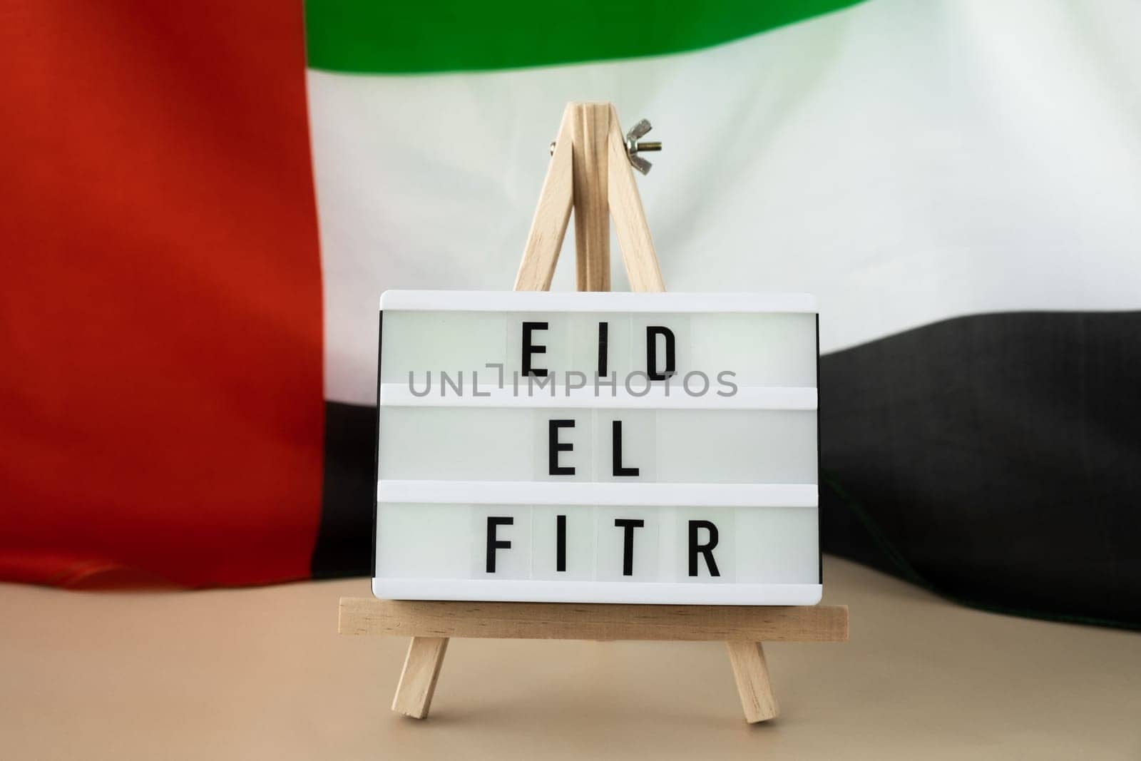 EID EL FITR - Eid Mubarak - Happy Holidays text frame on United Arab Emirates waving flag made from silk material. Public holiday celebration background. The National Flag of UAE. Commemoration Day Muslim Ramadan Blessed Holy Month concept by anna_stasiia