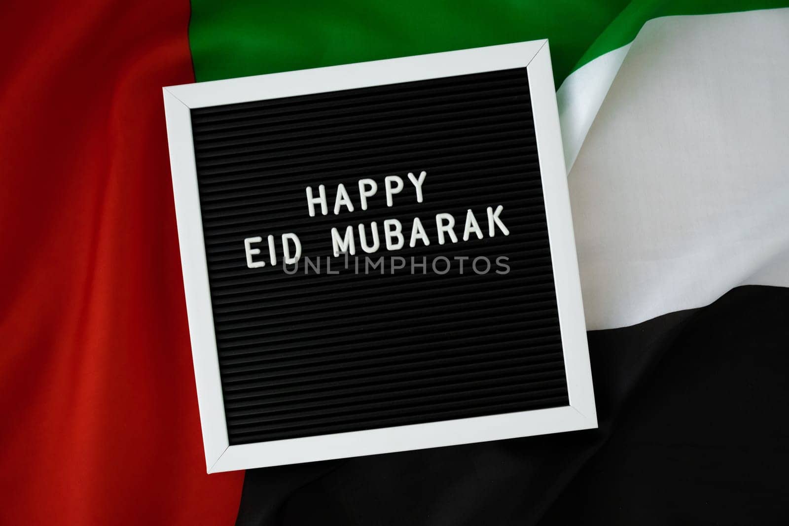 Congratulations with text HAPPY EID MUBARAK - happy holidays waving UAE flag on background concept. Greeting card advertisement. Commemoration Day Muslim Ramadan Blessed holy month public holiday by anna_stasiia