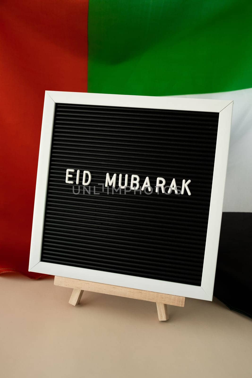 EID MUBARAK - happy holidays text frame on United Arab Emirates waving flag made from silk material. Public holiday celebration background. The National Flag of UAE. Patriotism Muslim Ramadan Blessed Holy Month concept