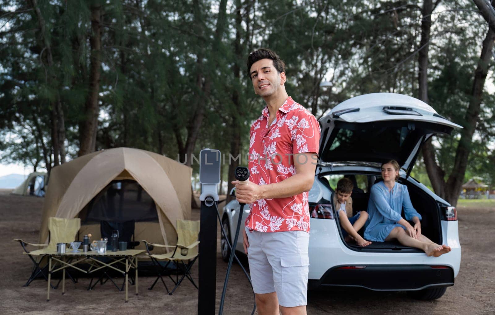 Lovely family recharge EV car with EV charging station in campsite. Perpetual by biancoblue