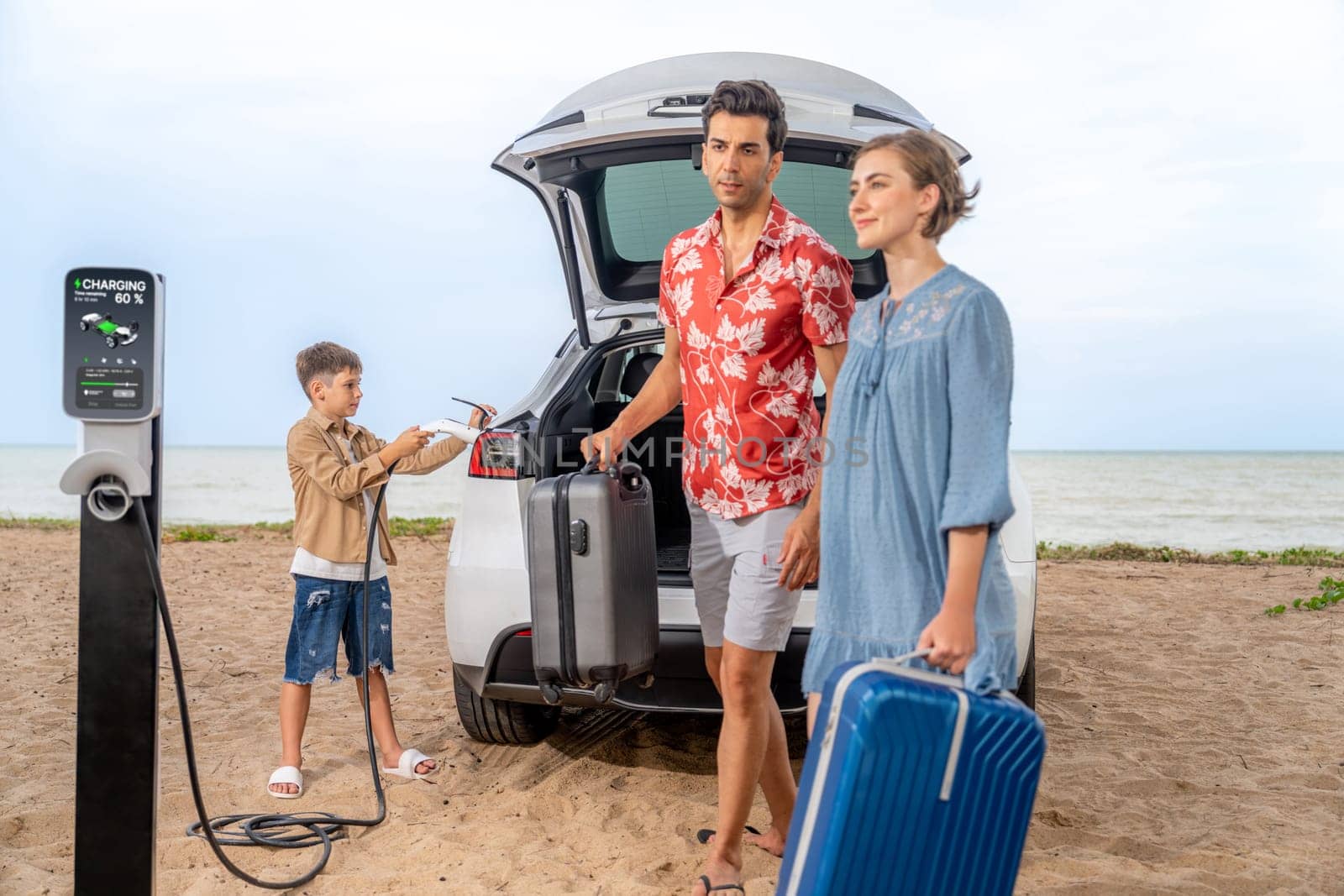 Family vacation trip traveling by the beach with electric car, lovely family taking luggage out while charging EV car battery with clean energy. Alternative family travel by eco-friendly car.Perpetual