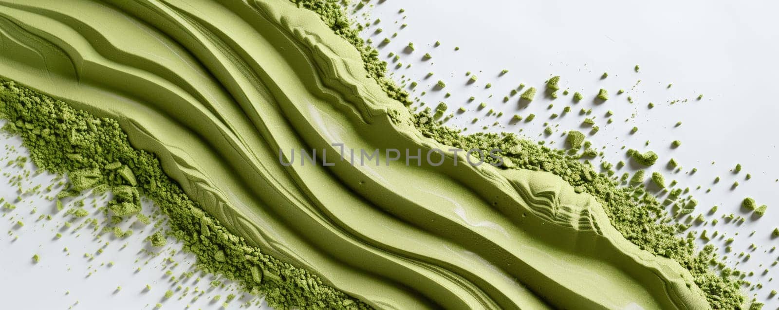 A detailed view of a bright green substance spread out on a clean white surface. The substance appears thick and slightly textured, with vibrant hues contrasting against the neutral background.