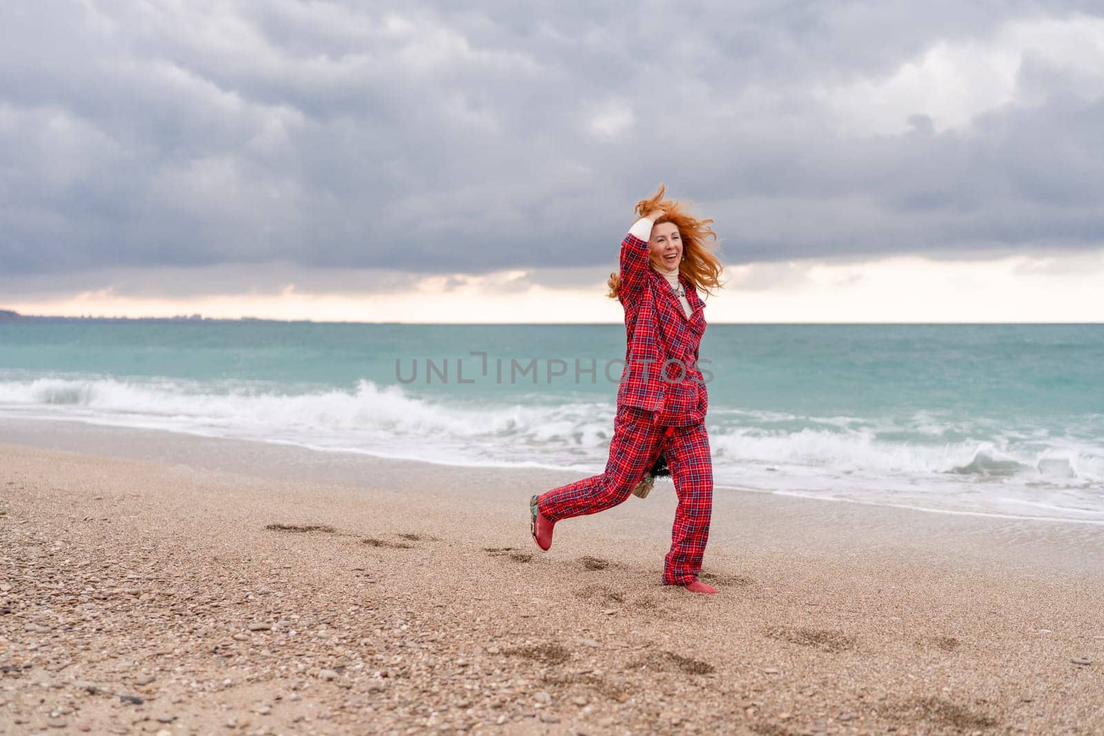 Sea Lady in plaid shirt with a christmas tree in her hands enjoys beach. Coastal area. Christmas, New Year holidays concep.