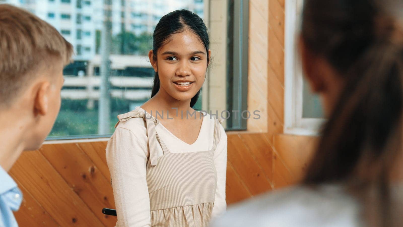 Young student smiling while listening other student in meeting or group discussion. Cute teenager talking about her experience and sharing to friends in mixed races. Creative education. Edification.