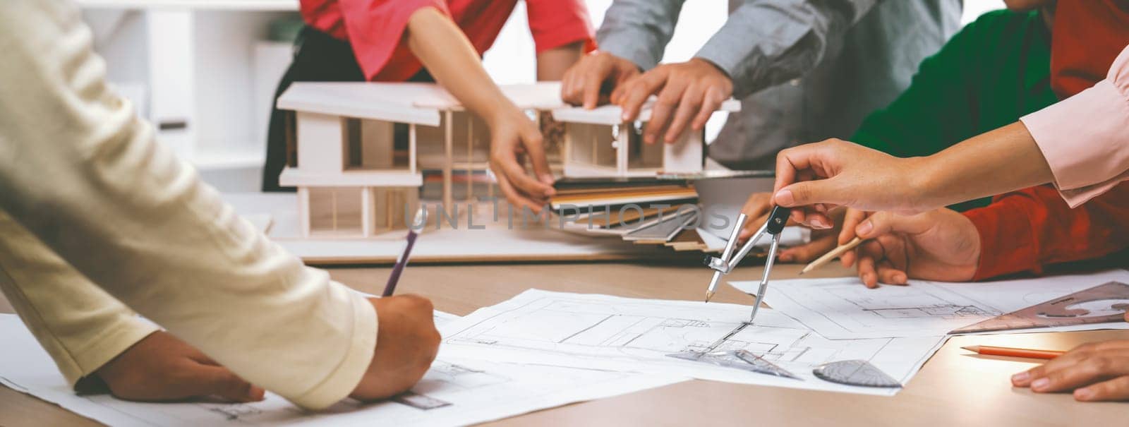 Professional architect team select sustainable house materials while skilled engineer using divider measure blueprint with house model and color palette placed on meeting table. Closeup. Variegated.