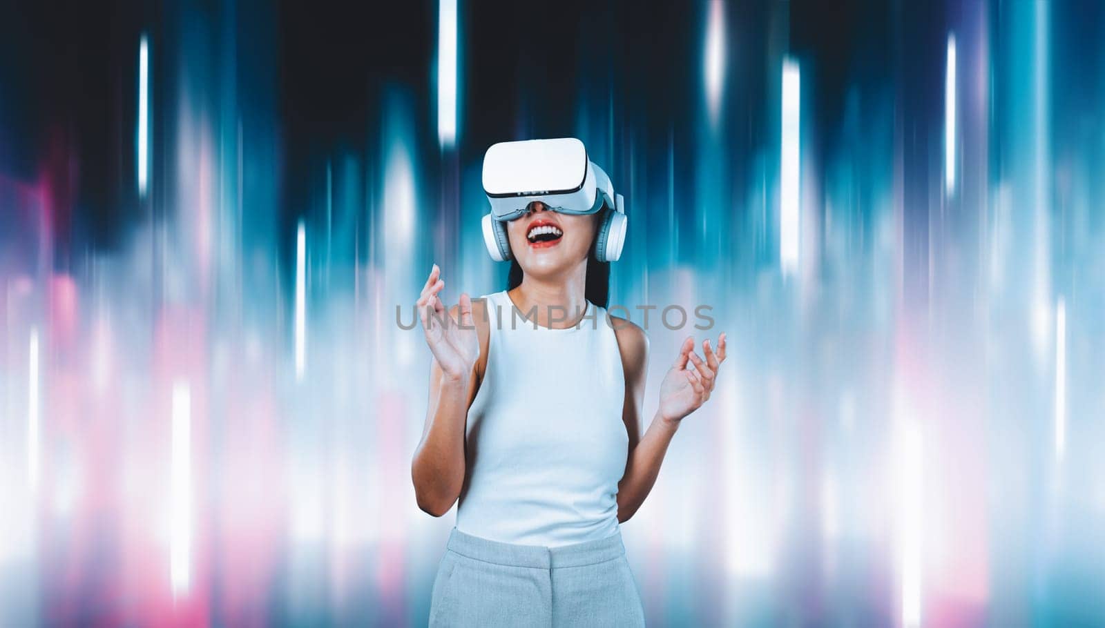 Female standing and wearing white VR headset and white sleeveless connect metaverse, future technology creating cyberspace community. She enjoy look fantasy abstract light around her. Hallucination.