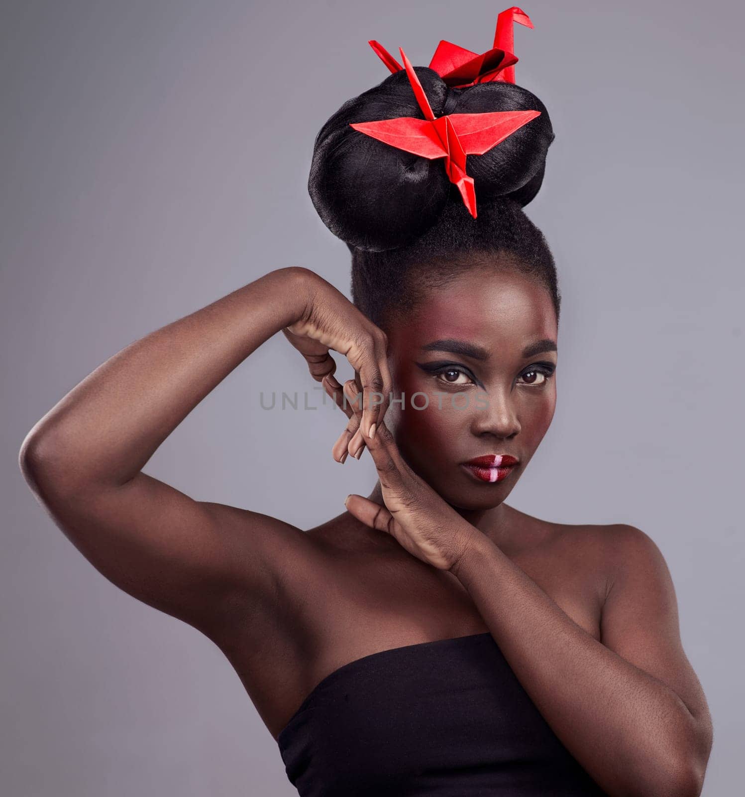 Woman, makeup portrait and origami in studio for beauty with red, oriental culture and paper bird. African model, bold cosmetics and grey background for art deco, confidence and creative with design.