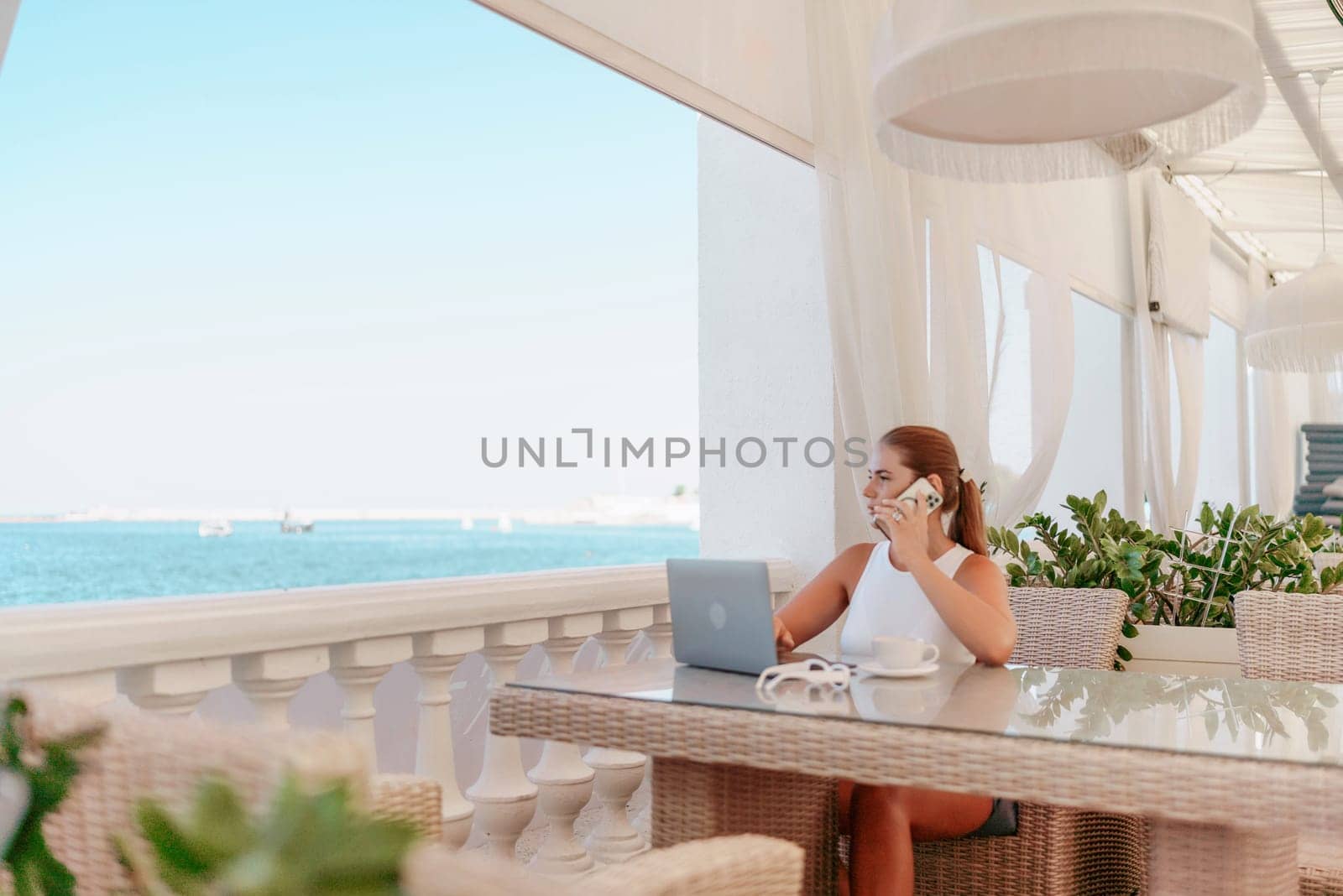 Woman coffee cafe laptop sea. Modern businessman in white uniform working on laptop in coffee shop. Woman sitting at a coffee shop with mobile phone drinking coffee