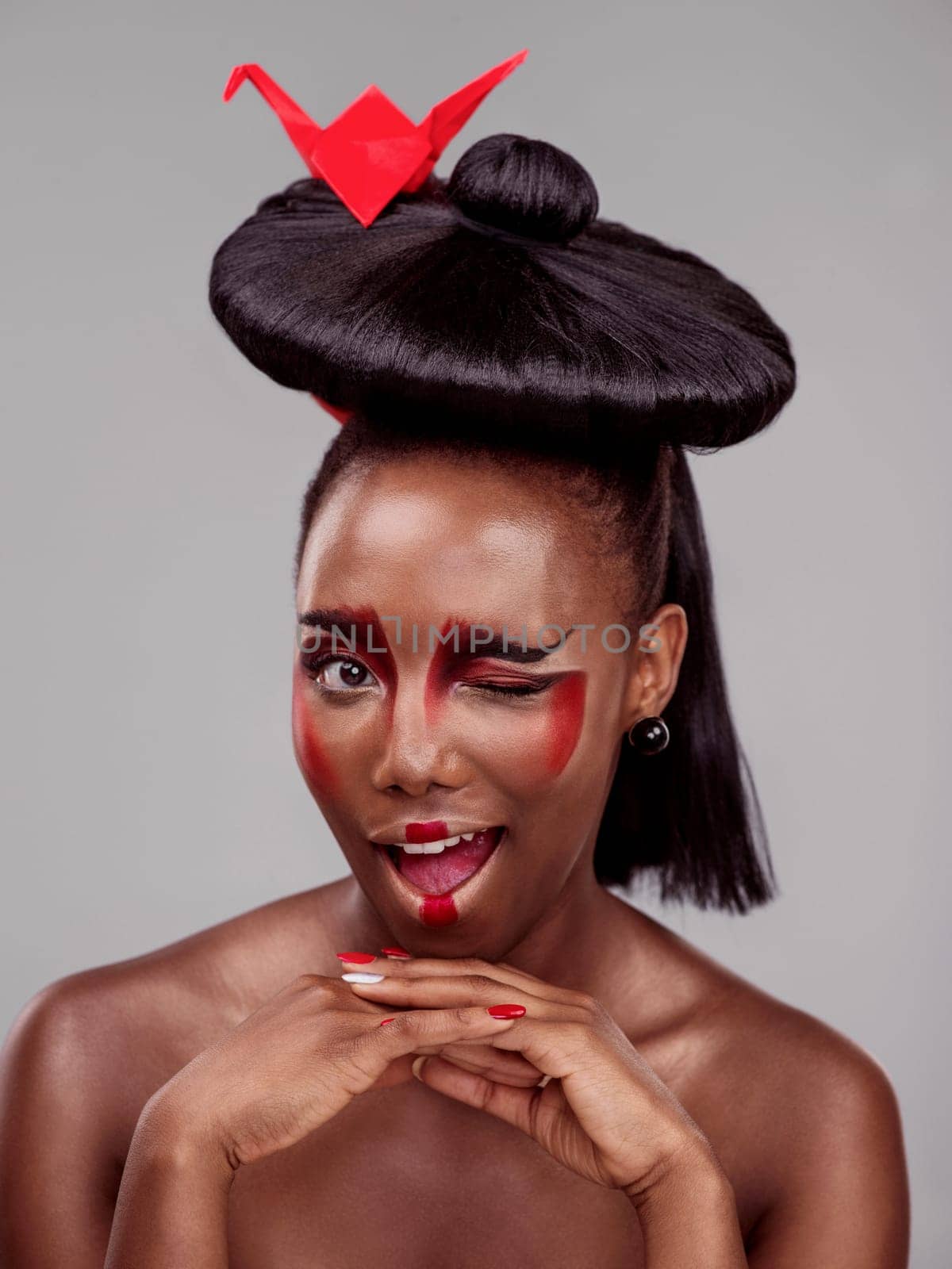 Creative beauty, wink and black woman with origami in studio isolated on dark background. Funny face, makeup and skincare with African female model, traditional and Japanese paper for art deco by YuriArcurs