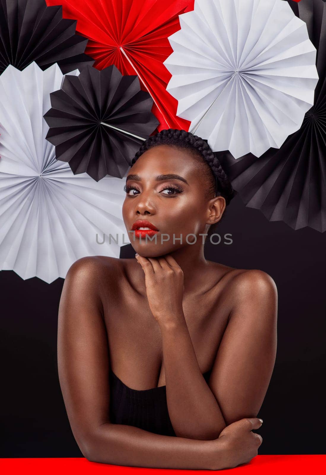 Creative, portrait and black woman with origami fans in studio, beauty and dark background. Face, makeup and cosmetics of female model with pride, traditional care and paper art for culture hat.