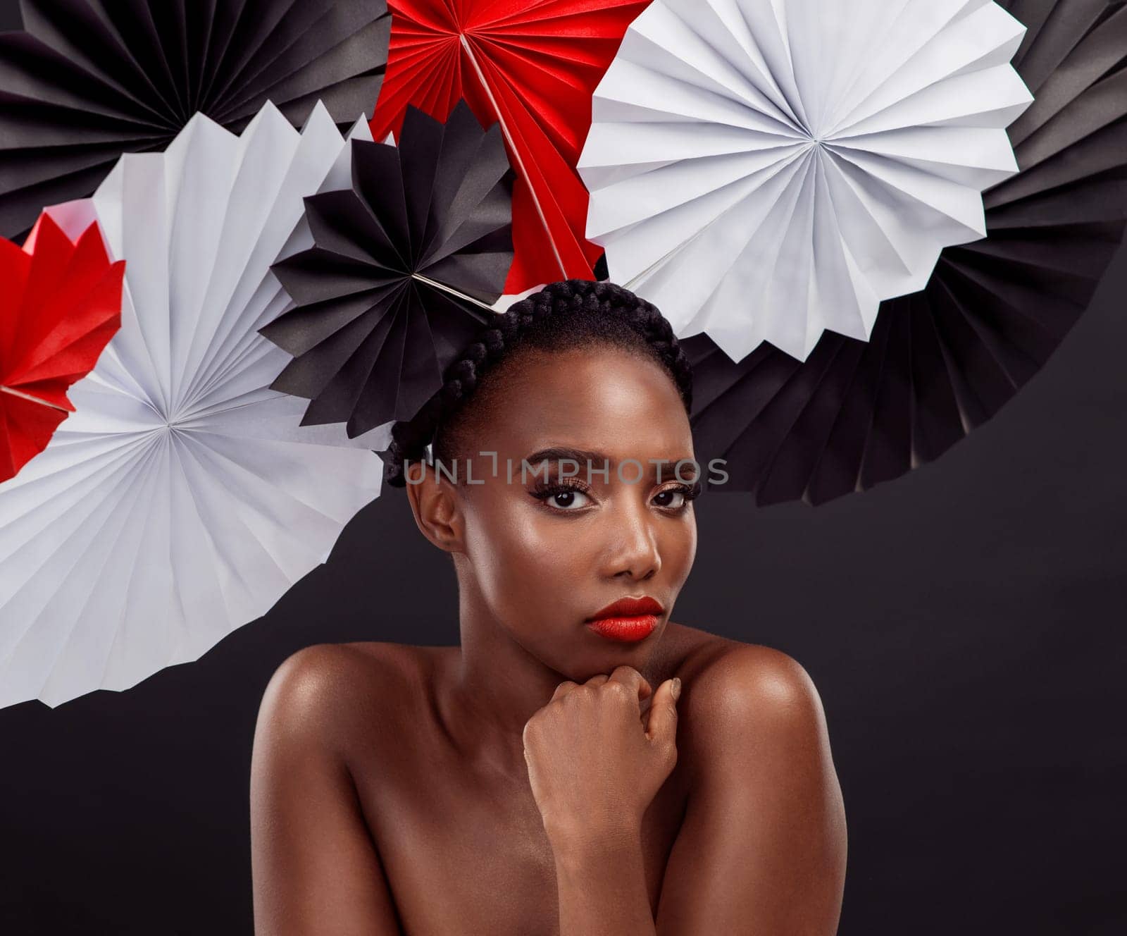 Woman, portrait and beauty with origami fans in studio isolated on a dark background. Face, makeup cosmetics and skincare of black female model with traditional Japanese paper art for culture hat.