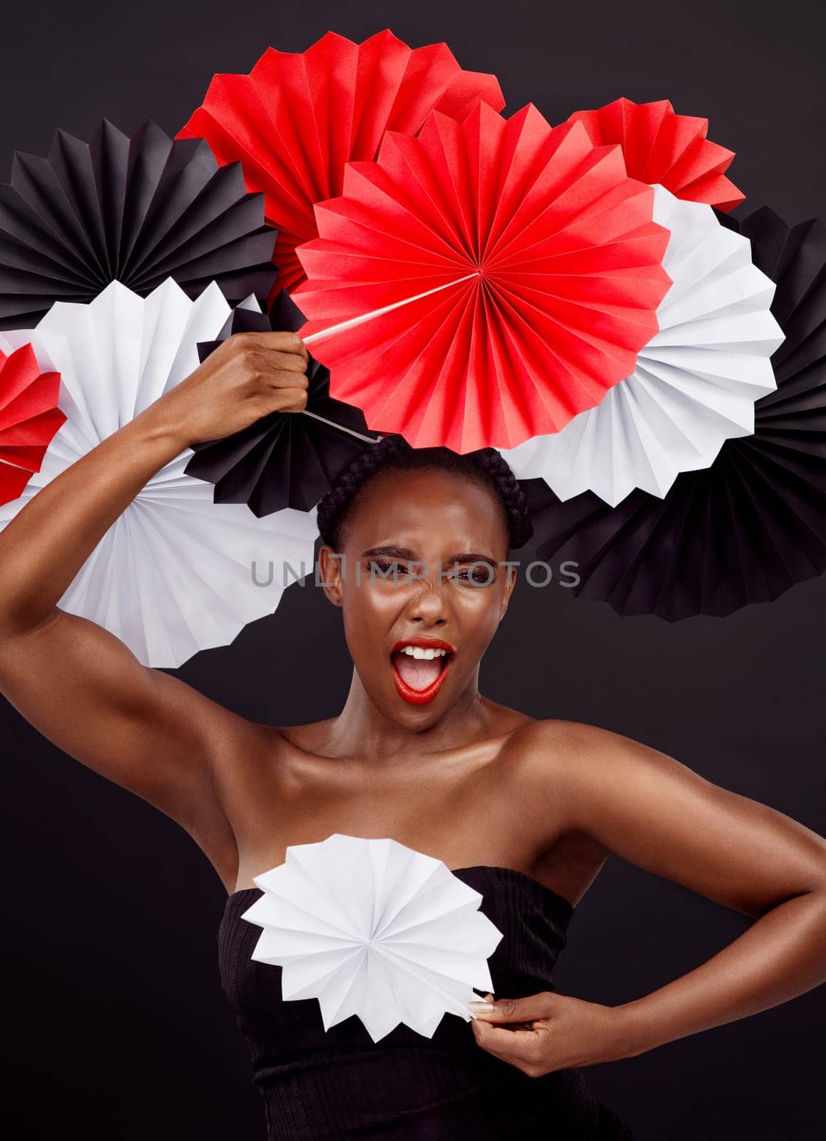 Woman, portrait and shout with origami fans in studio isolated on a dark background. Face, make up and excitement of black female model with traditional craft paper art for creative expression.