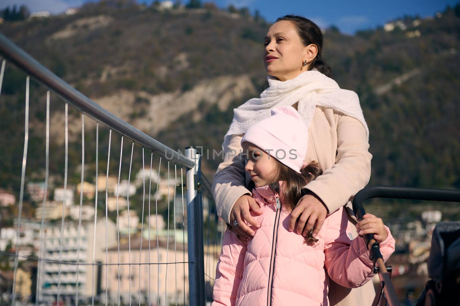 Happy woman and her little kid, cute daughter walking on the promenade near the lake of Como. Family relationships. Mother and children enjoying family walk outdoors, admiring beautiful lake of Como