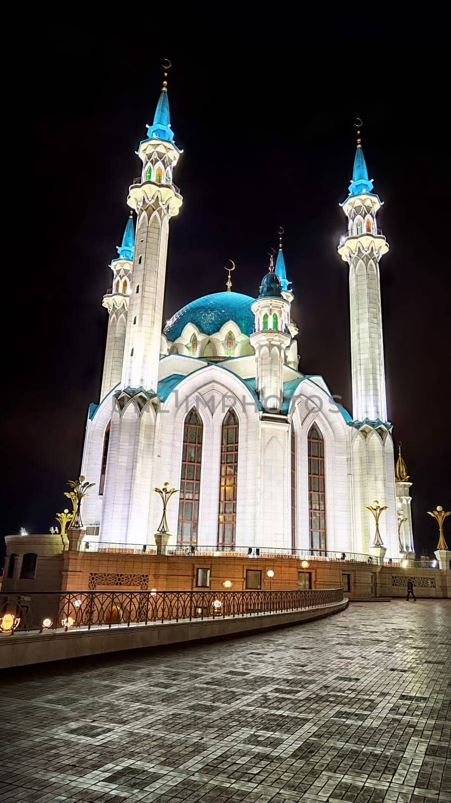 Beautiful white mosque with minarets against dark cloudy sky in night or evening. Ramadan Holiday