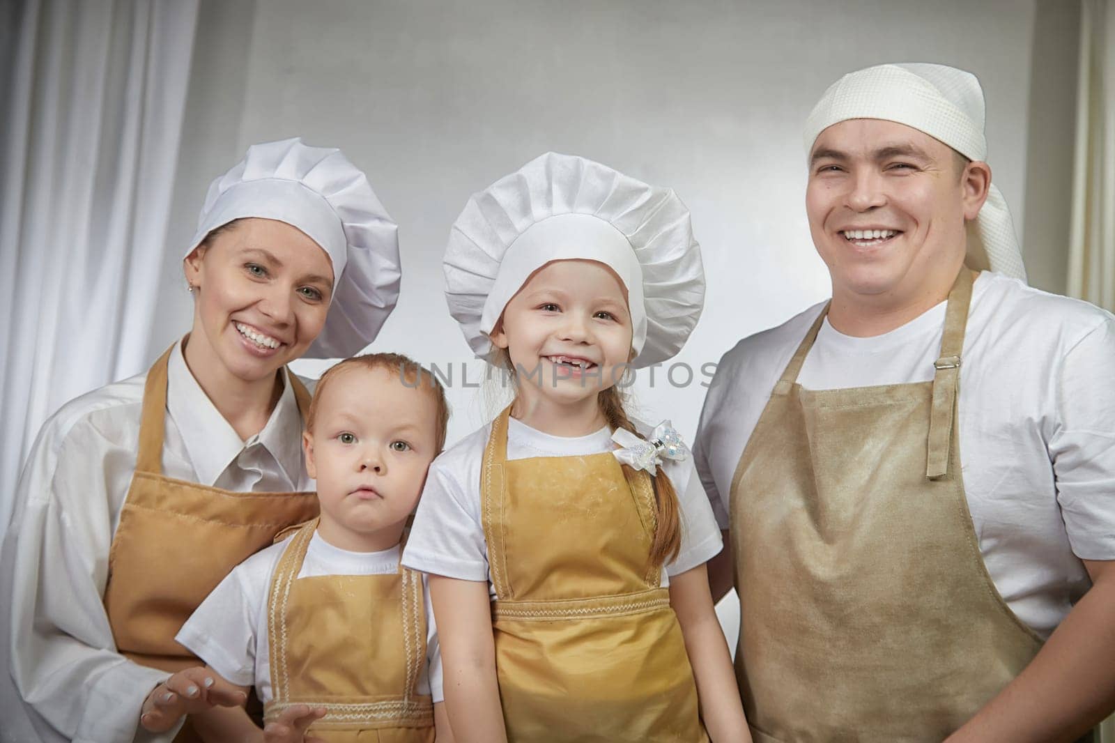 Cute oriental family with mother, father, daughter, son cooking in kitchen on Ramadan, Kurban-Bairam, Eid al-Adha. Funny family at photo shoot. Easter by keleny