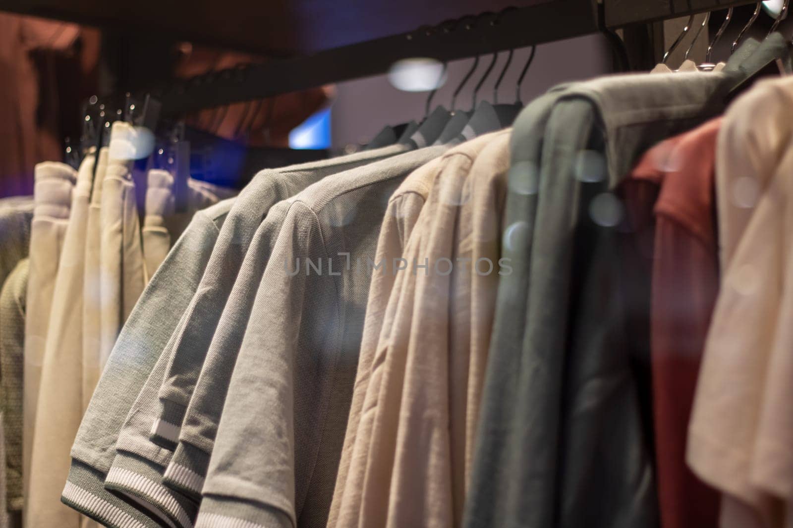 A row of Fashion design shirts, including Denim and Sportswear in Electric blue, are hanging on Clothes hangers in a Retail store