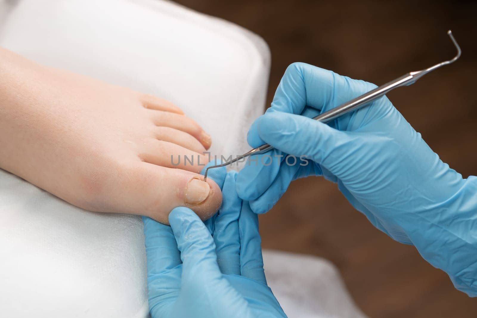 Pedicure master uses nail instrument while toe nails treatment.