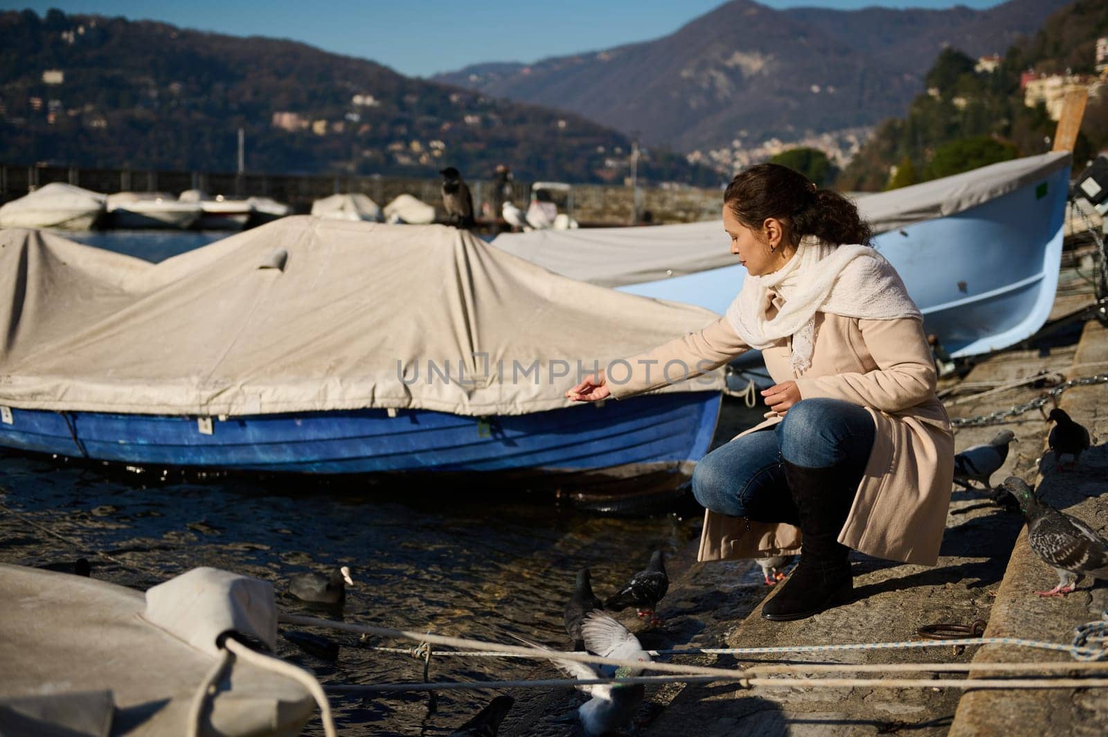 Pretty woman feeding swans and ducks on a winter lake of Como by artgf