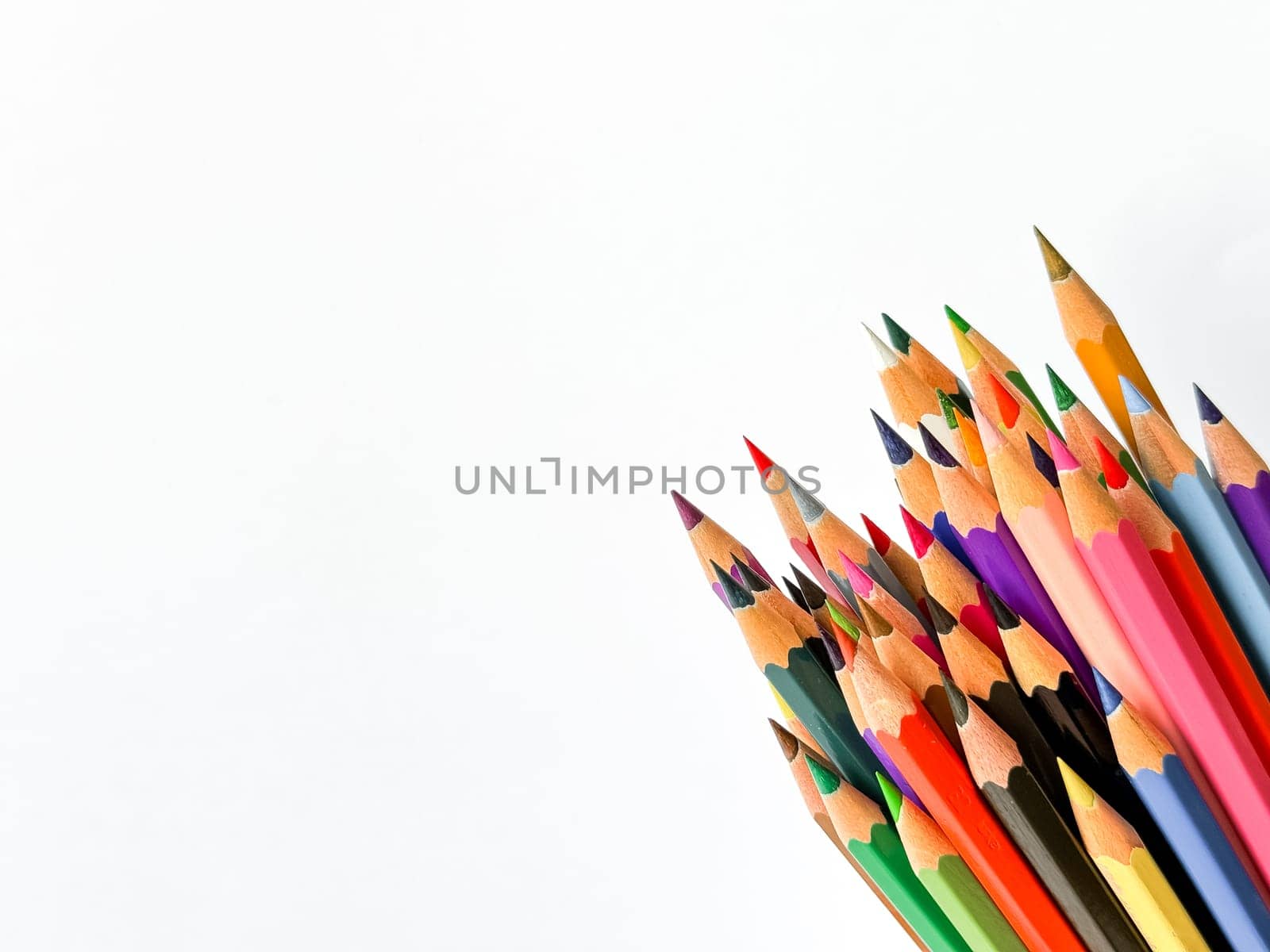 Assorted sharpened colorful pencils pointing up on white background with copy space for text. Concept of artistic or school supplies for design, teaching and educational purposes. High quality photo