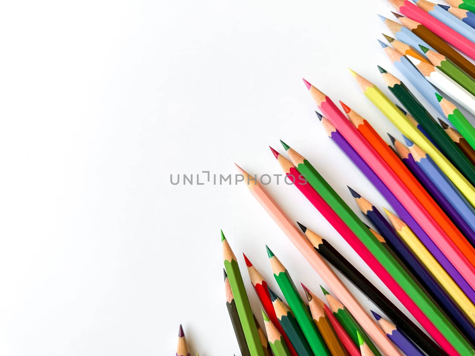 Assorted sharpened colorful pencils pointing up on white background with copy space for text. Concept of artistic or school supplies for design, teaching and educational purposes. High quality photo