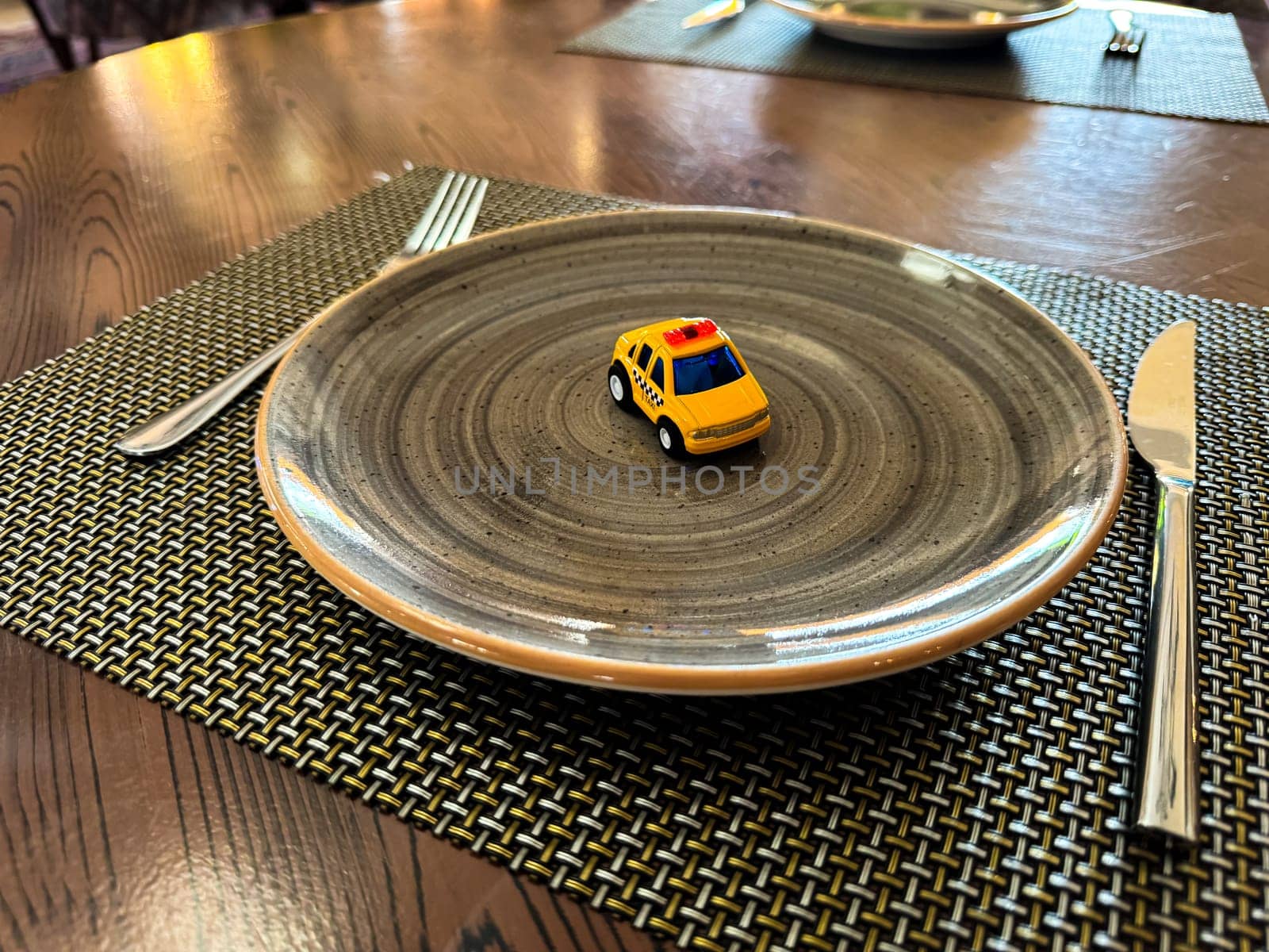Miniature taxi toy on ceramic plate with cutlery. Concept of calling taxi after end of banquet or celebration. Design of taxi advertising, culinary presentations and unusual concepts. by Lunnica
