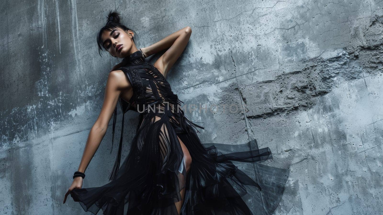 Fashion model striking a pose in an edgy, black textured dress against a concrete backdrop