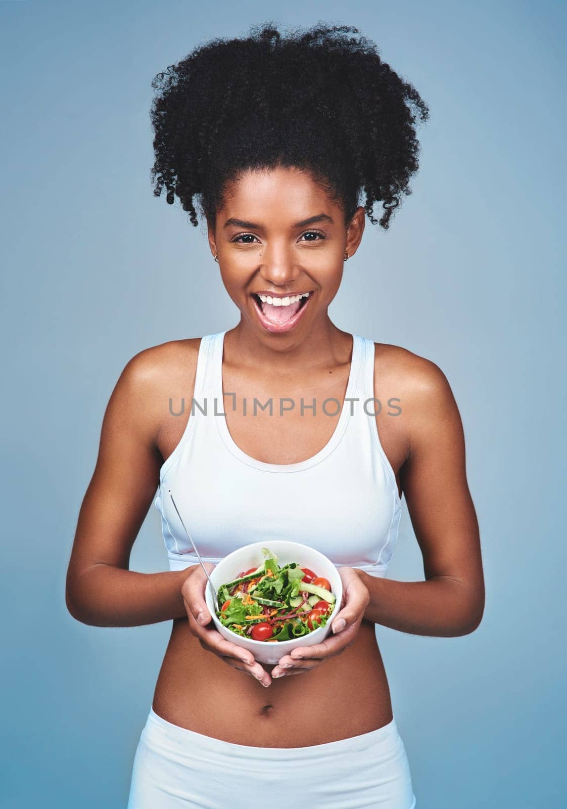 Smile, portrait or black woman with salad in studio for healthy meal, nutrition diet or digestion benefits. Body, vegetables and happy female fitness model eating food isolated on blue background.