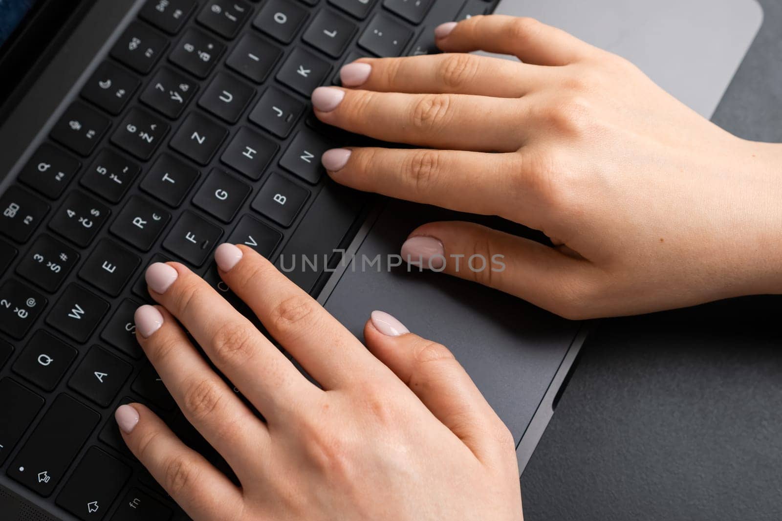 Woman working by using a laptop keyboard on a black table. by vladimka