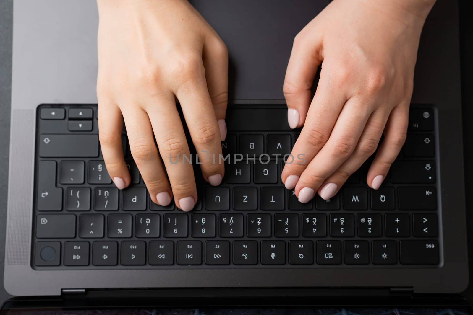 BERLIN, GERMANY - APRIL 14 2024: Female hands on the black keyboard, top view.