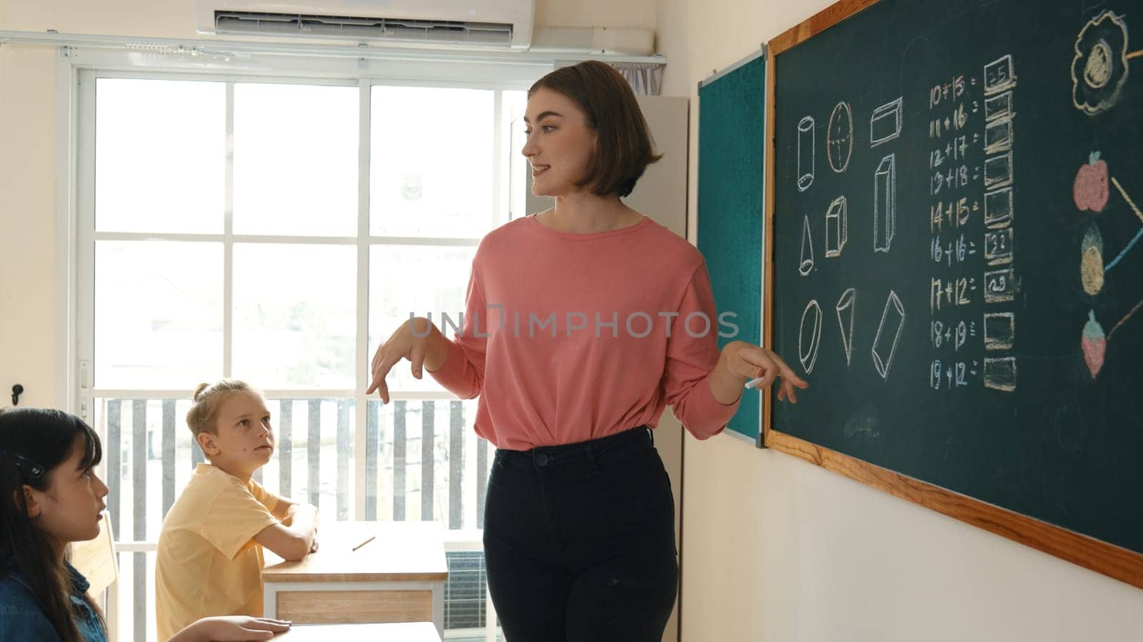 Caucasian teacher request student to raise hand up to answer question at in front of classroom. Attractive instructor calling children for writing answer in math lesson at elementary school. Pedagogy.