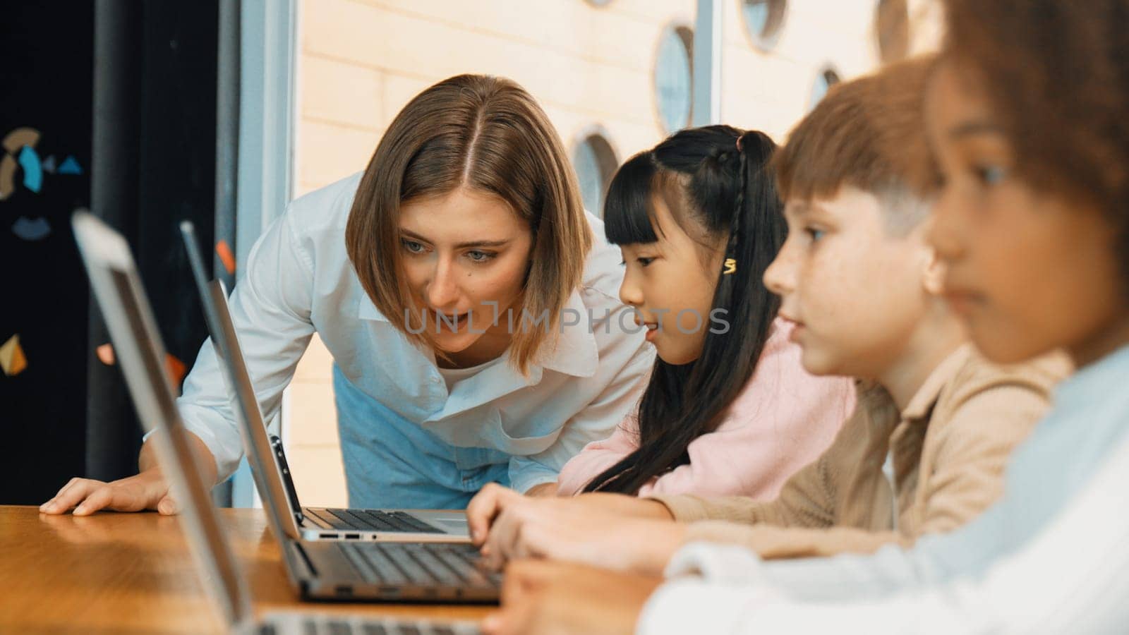 Smart teacher teaching and looking student using laptop at classroom. Professional instructor explained about programing engineering code or prompt while studying and learning program. Erudition.