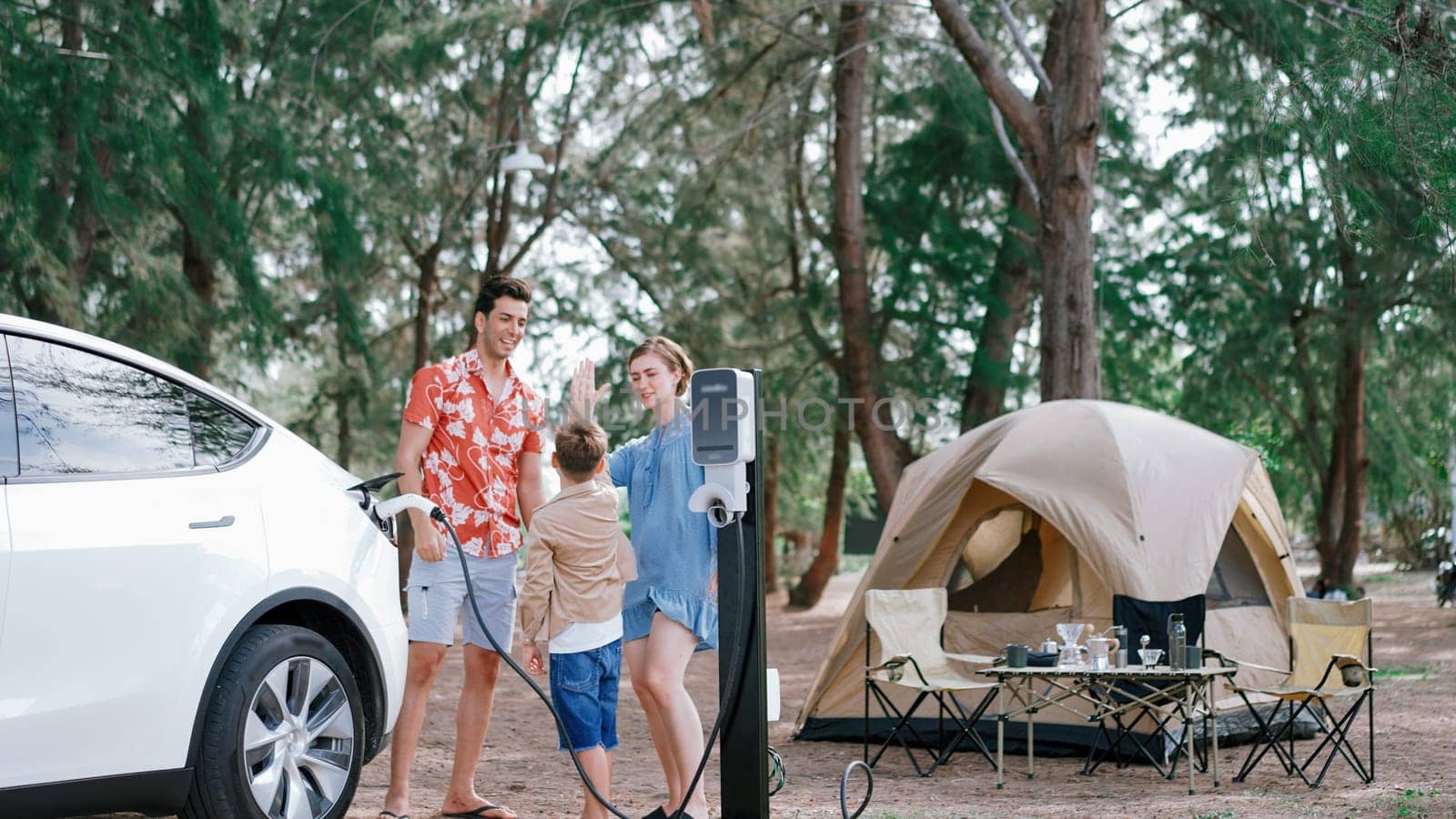 Lovely family recharge EV car with EV charging station in campsite. Perpetual by biancoblue