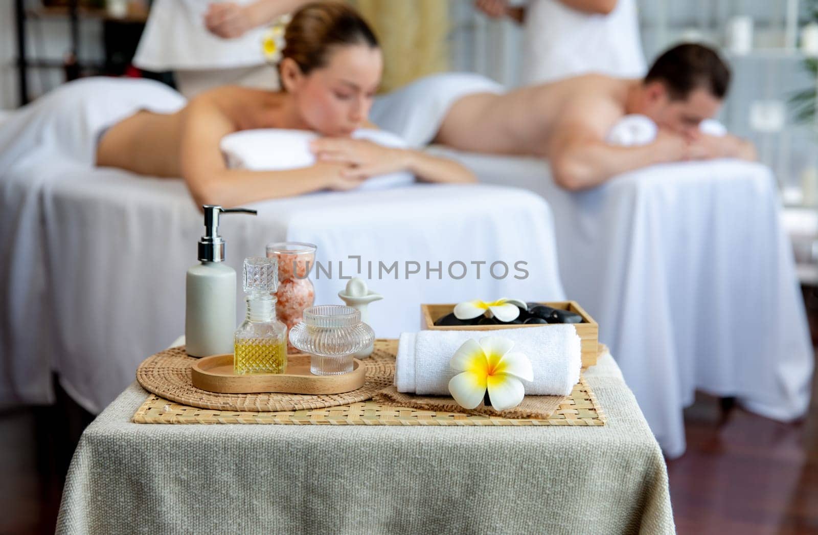 Aromatherapy massage on daylight ambiance or spa salon composition setup with focus decor and spa accessories on blur woman enjoying blissful aroma spa massage in resort or hotel background. Quiescent