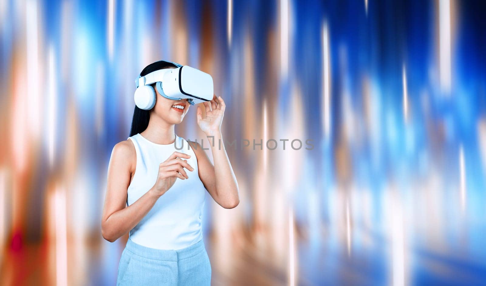 Female standing and wearing white VR headset and white sleeveless connect metaverse, future technology creating cyberspace community. She enjoy look fantasy abstract light around her. Hallucination.