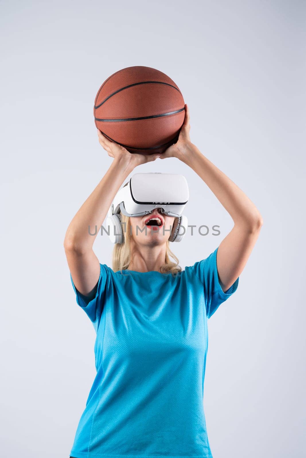 Girl wearing visual reality glasses and casual cloth and holding basketball. Caucasian woman playing basketball while standing at pink background at sport arena hologram. Innovation. Contraption.