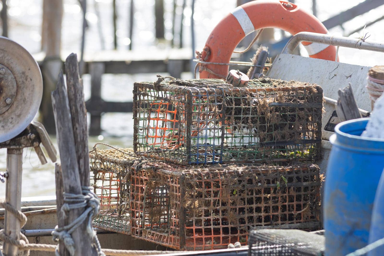 A boat with a blue container and two rusty fishing cages - trap for crabs by Studia72