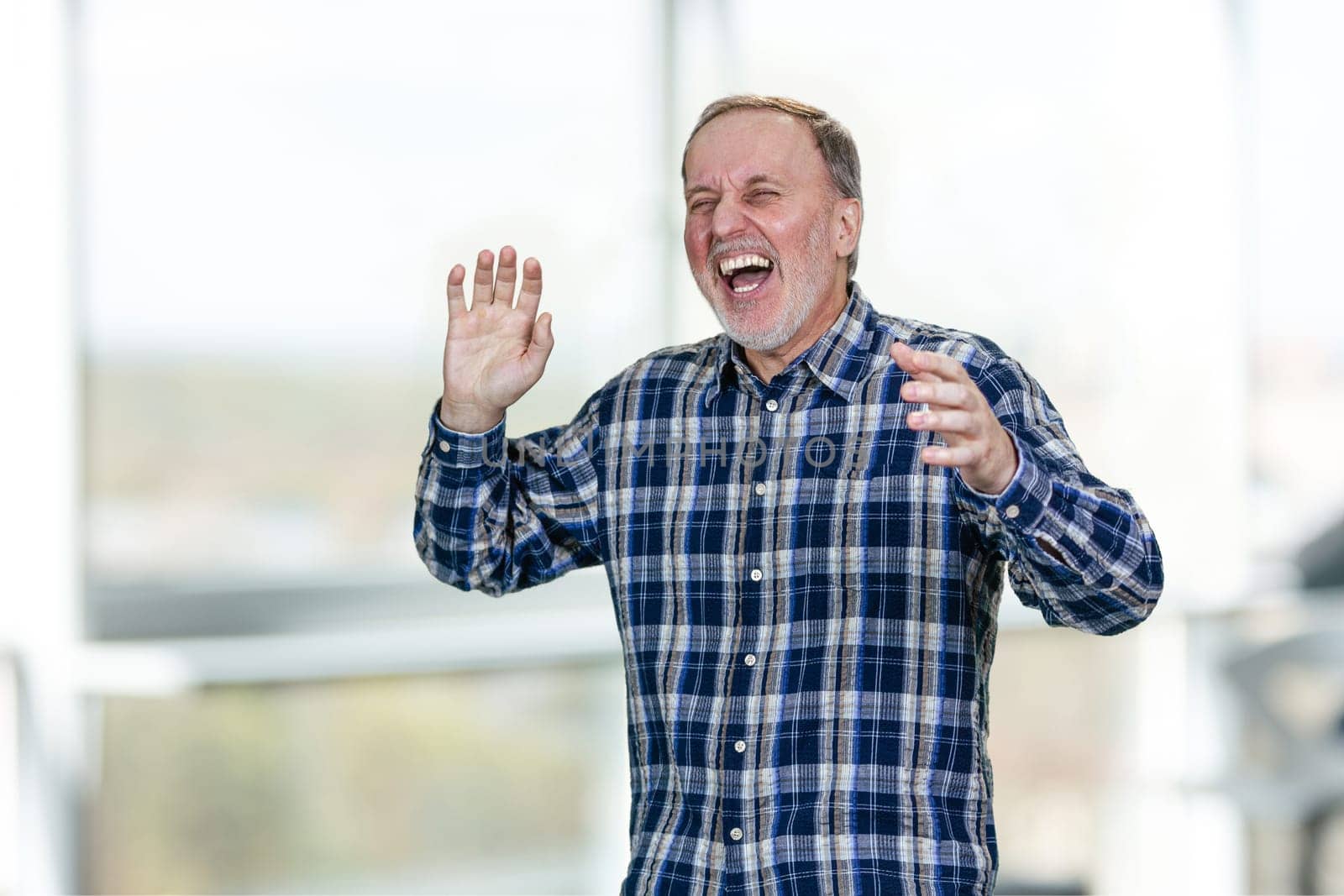Portrait of handsome middle aged man is laughing out loud. Bright indoor background.
