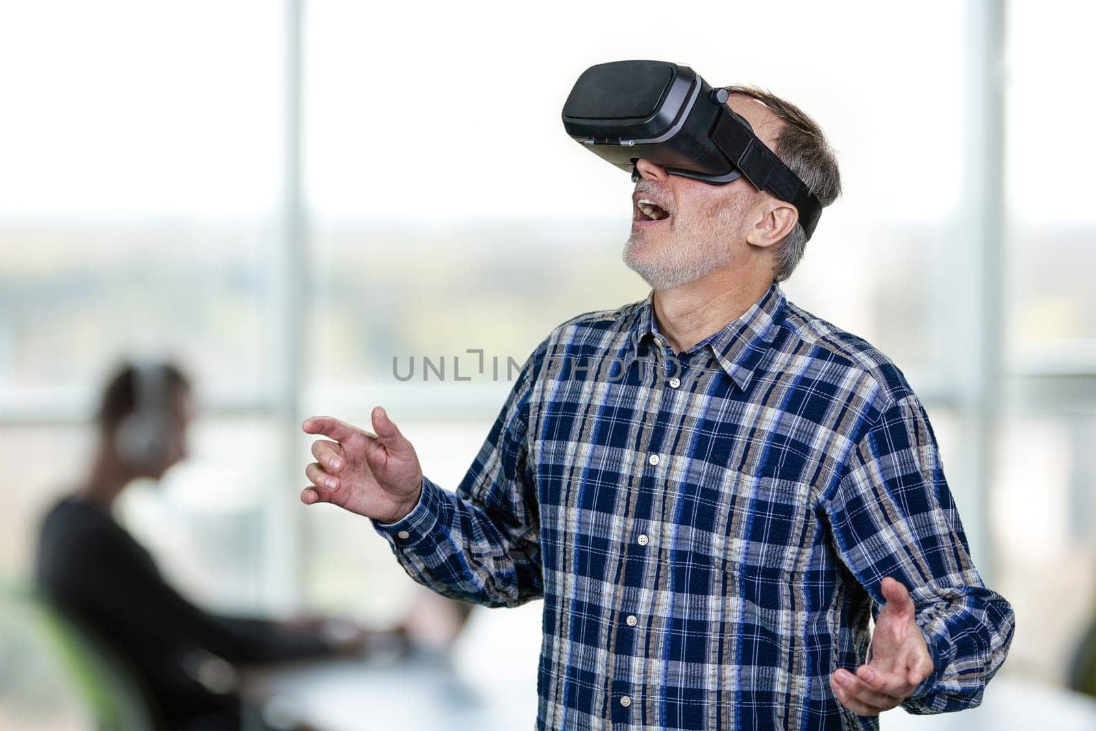 Excited elder man wearing vr headset with his mouth open. Indoor office enviroment background.