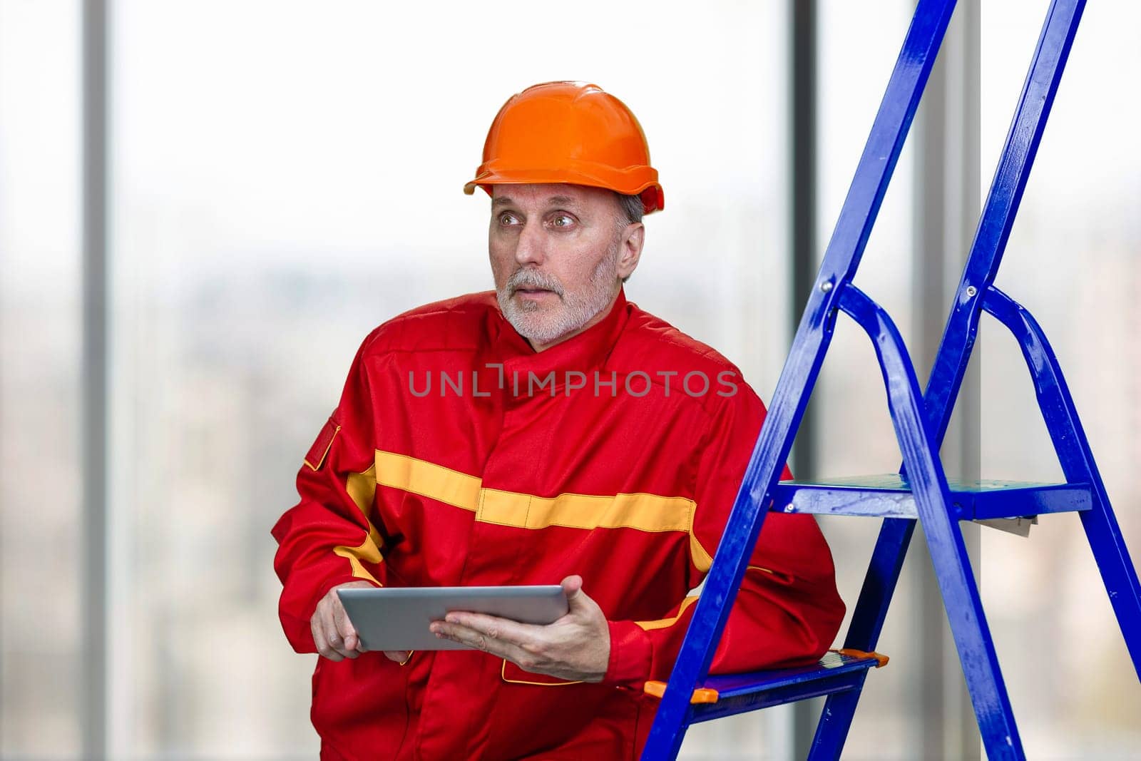 Portrait of elder caucasian contruction worker is using tablet device. by super_picture